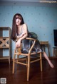 A woman sitting on a wooden chair in a room.