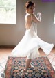 A woman in a white dress is dancing on a rug.