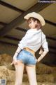 A woman in a cowboy hat and denim shorts posing for a picture.