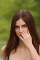 A woman with long brown hair covering her mouth with her hand.