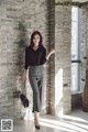 A woman standing in front of a brick wall.