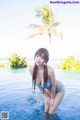 A woman in a blue bikini sitting in a pool.