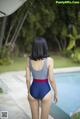 A woman in a blue and red bathing suit standing by a pool.