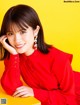 A woman in a red dress sitting on a yellow table.